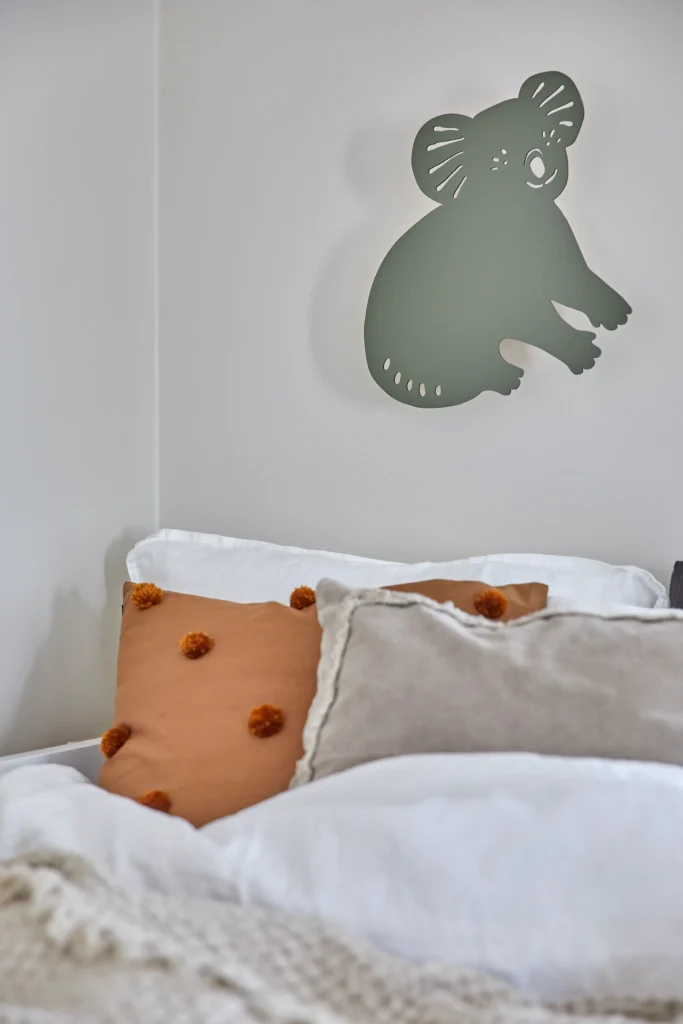 Pehmeä lastenhuoneen sänky ja tyynyasetelma seinäkoristeella – sisustussuunnittelu Lohja