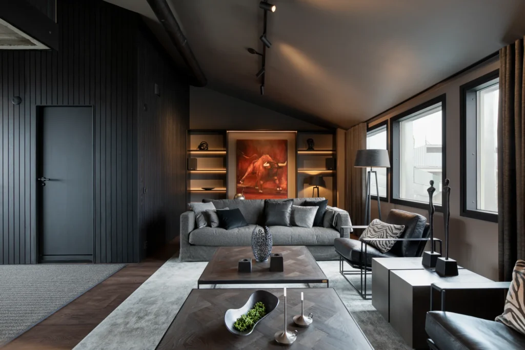 Moderni olohuone tummassa sävymaailmassa, design-sohva ja valaistu taideseinä – sisustussuunnittelu Helsingissä