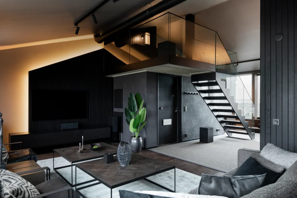 Avoin loft-tila parvella ja portailla, tummat materiaalit ja minimalistinen sisustussuunnittelu Helsingissä
