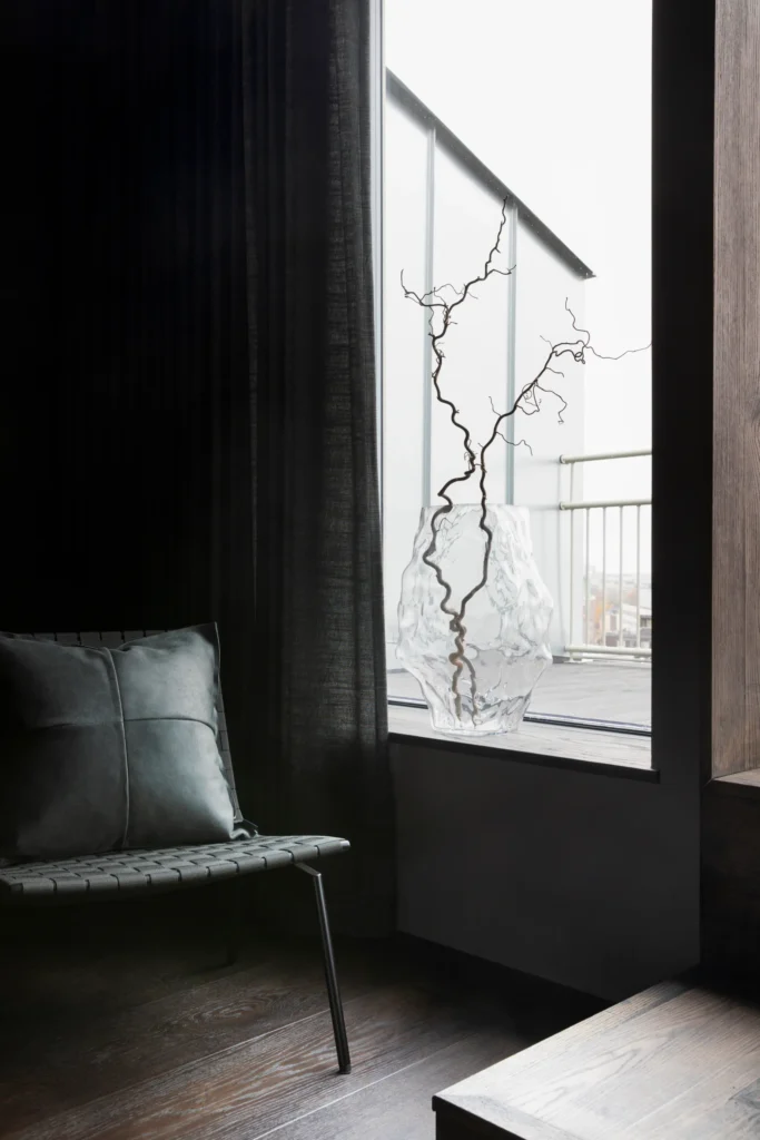 Moderni lasimaljakko ja oksa ikkunalla, viimeistelty yksityiskohta – sisustussuunnittelu Helsingissä