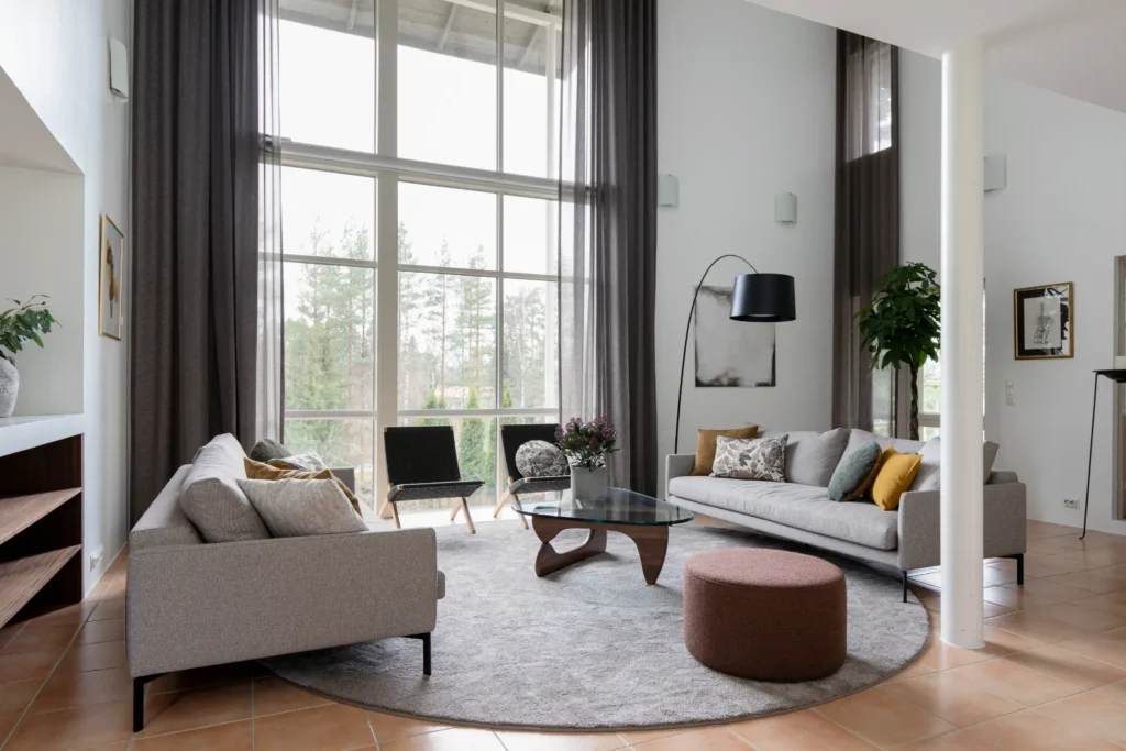 Avara olohuone korkealla tilalla ja suurilla ikkunoilla – sisustussuunnittelu Espoo Nuuksio