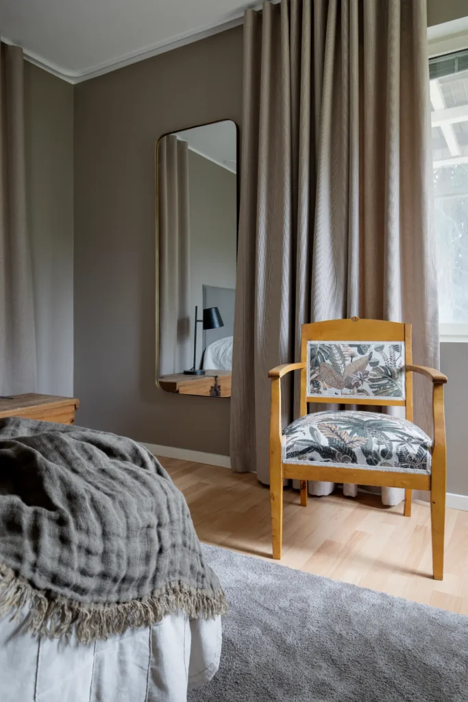 Makuuhuoneen yksityiskohta nojatuolilla ja pehmeällä valaistuksella – sisustussuunnittelu Espoo Nuuksio
