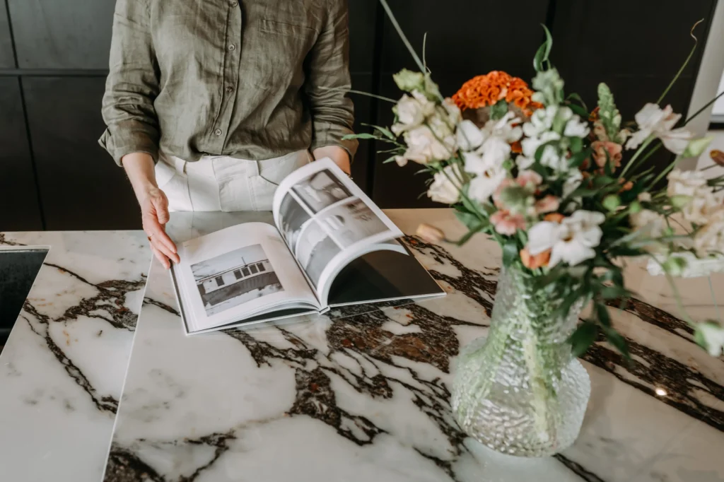 sisustussuunnittelija selaa sisustuslehteä keittiössä – sisustussuunnittelu Espoo Saunalahti