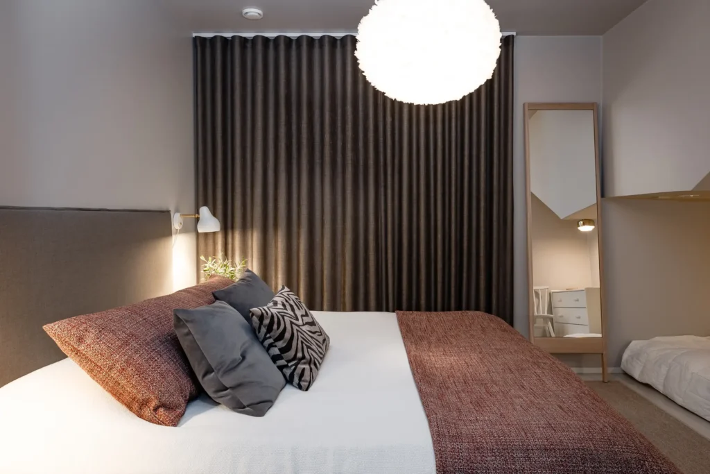 Tunnelmallinen makuuhuone tummilla verhoilla ja valaistuksella – sisustussuunnittelu Espoo Soukka